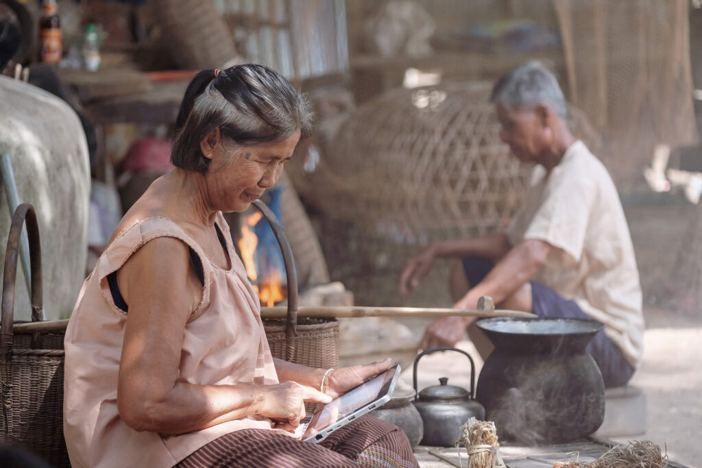 woman sitting by cooking pots while looking at a tablet