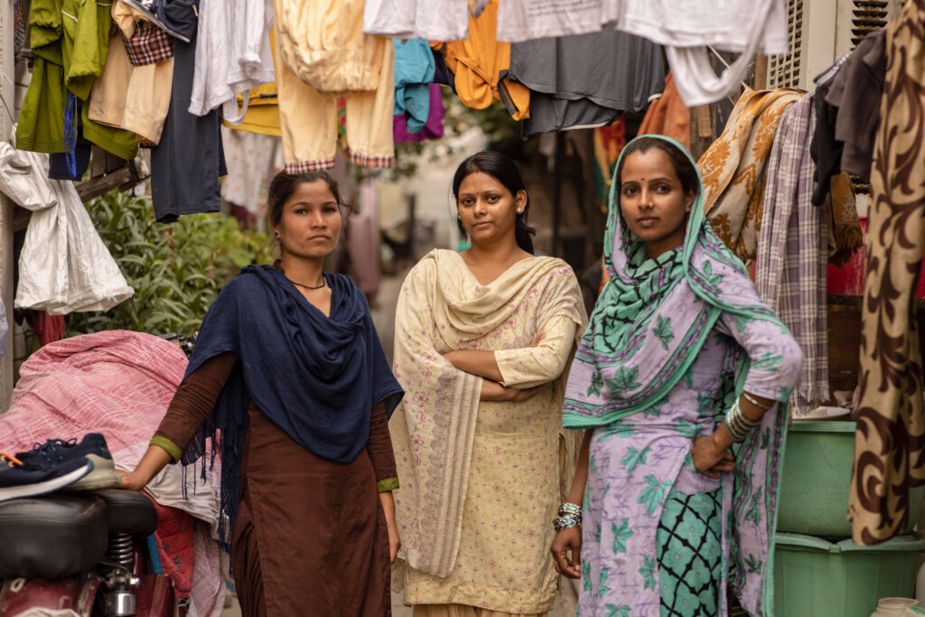 three women surrounded by hanging clothing