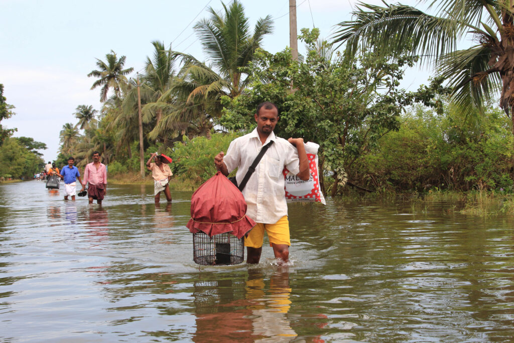 man carrying a birdcage through water