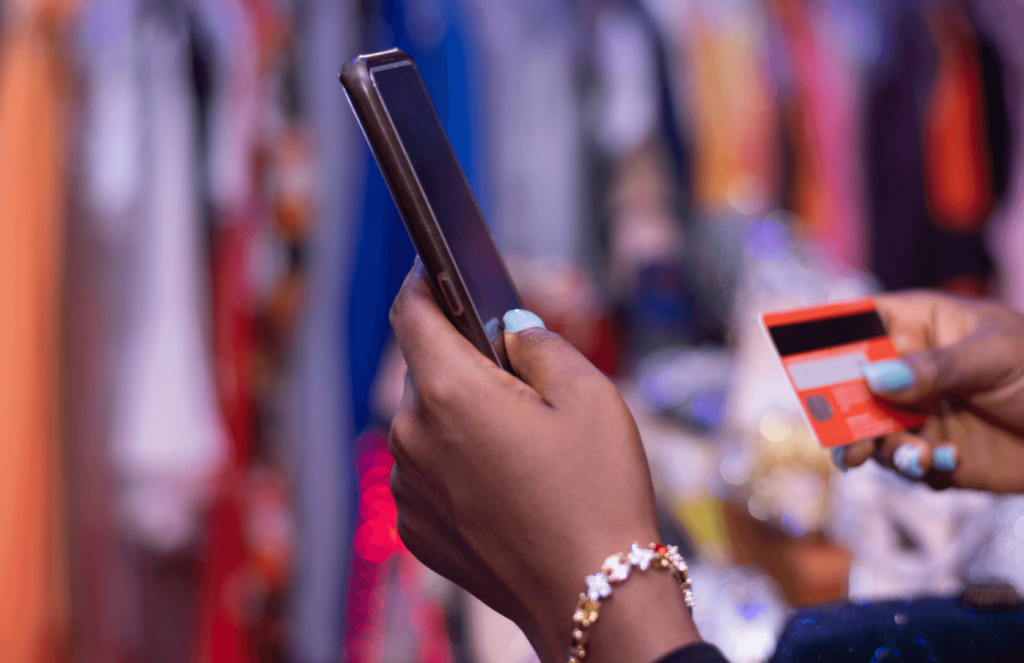 Person holding cell phone in one hand and credit card in the other